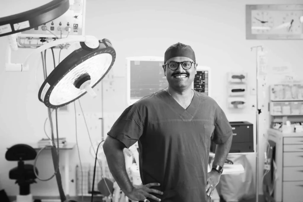 Black and white photo of Dr Ganesh Shiva in surgical attire, standing in an operating theatre before performing a peripheral nerve tumour biopsy